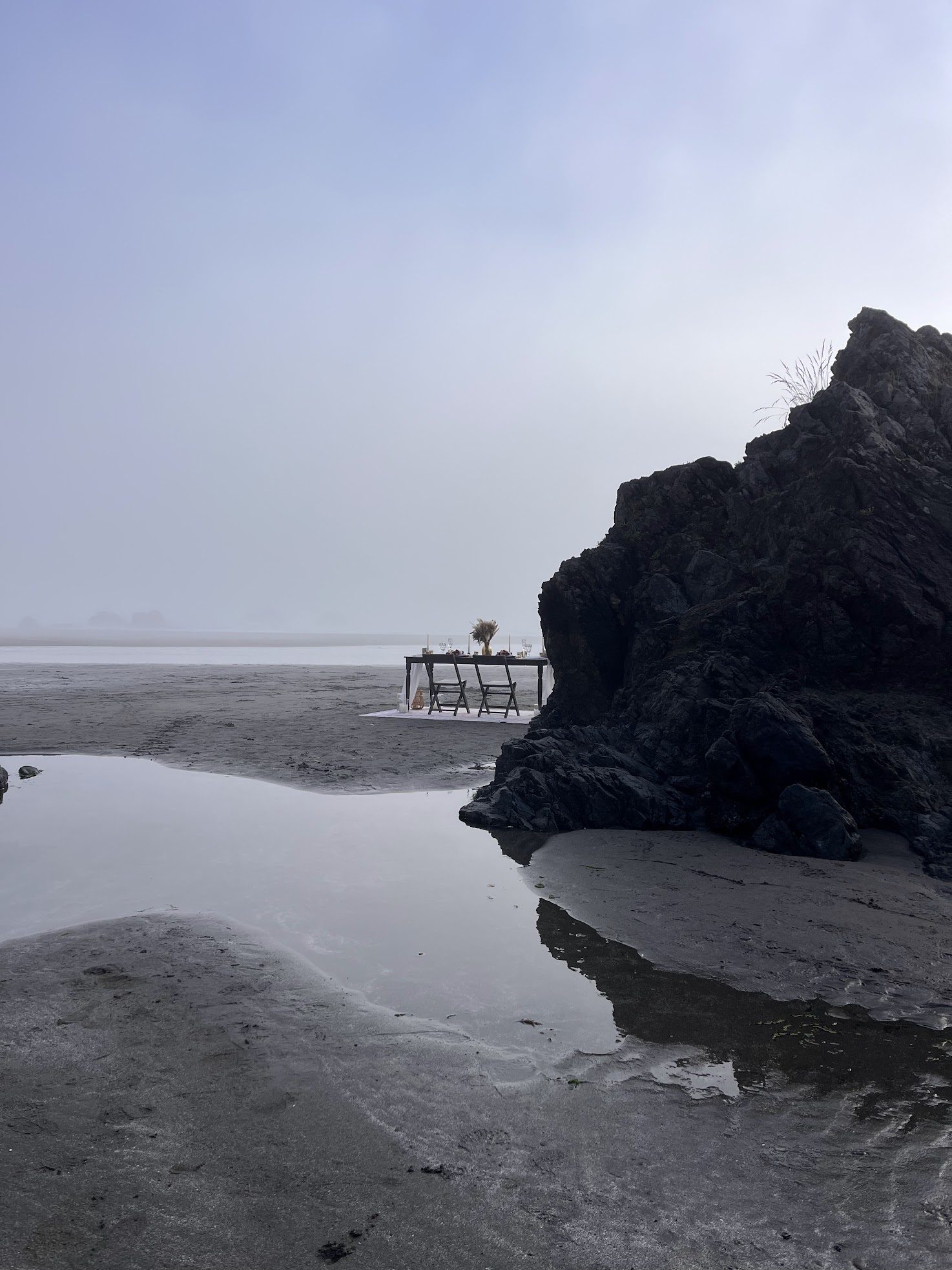 Sweetheart table for two set beside a dark rock on a foggy morning at Whaleshead Beach.