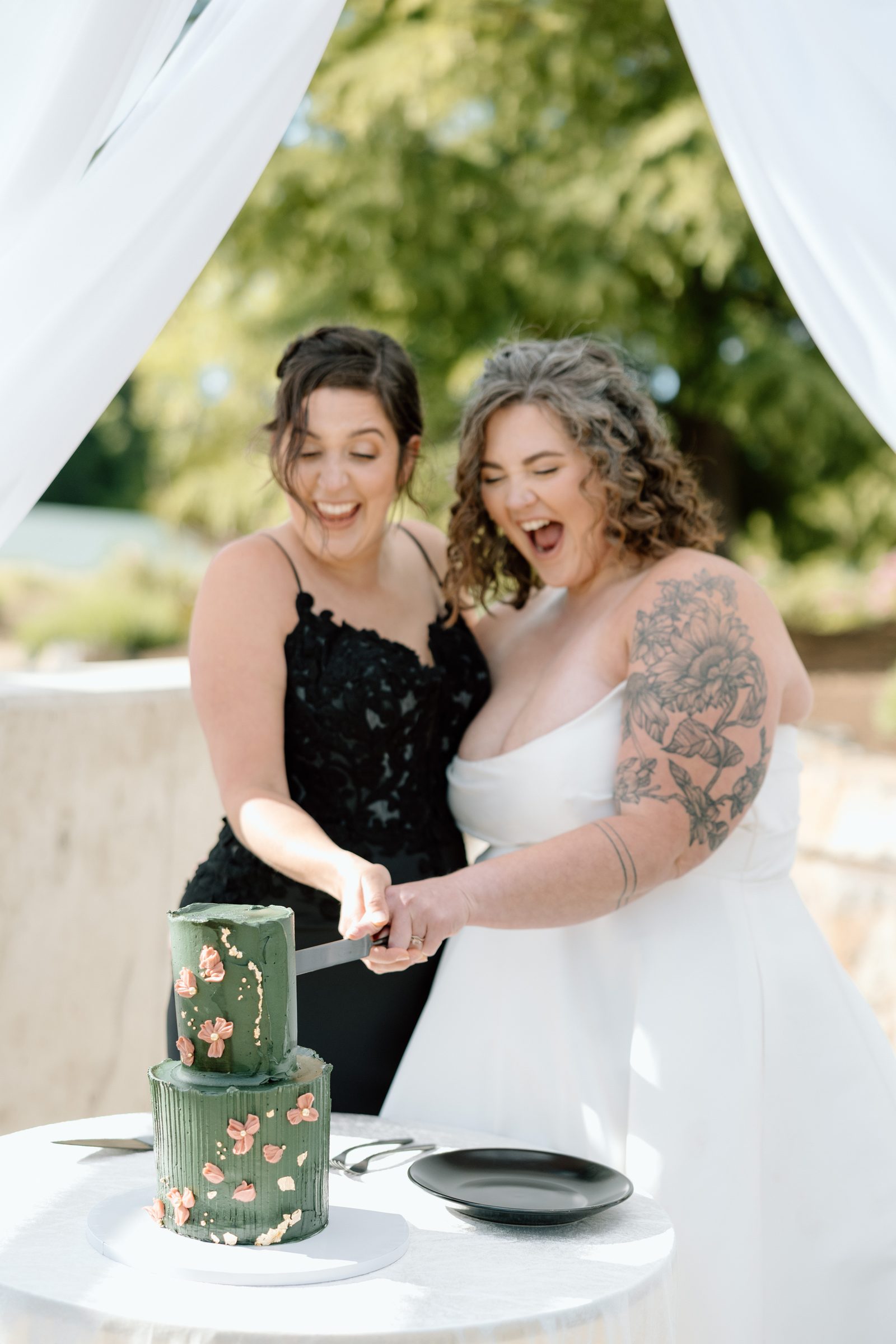 Couple cutting a green floral wedding cake.