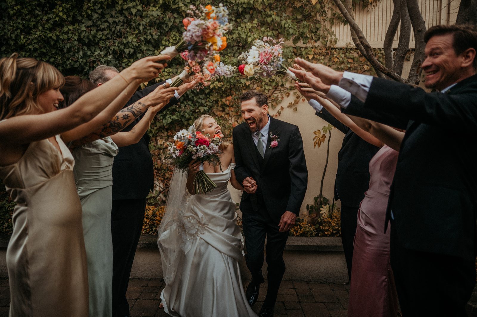Guests tossing flowers over a couple during their wedding exit.
