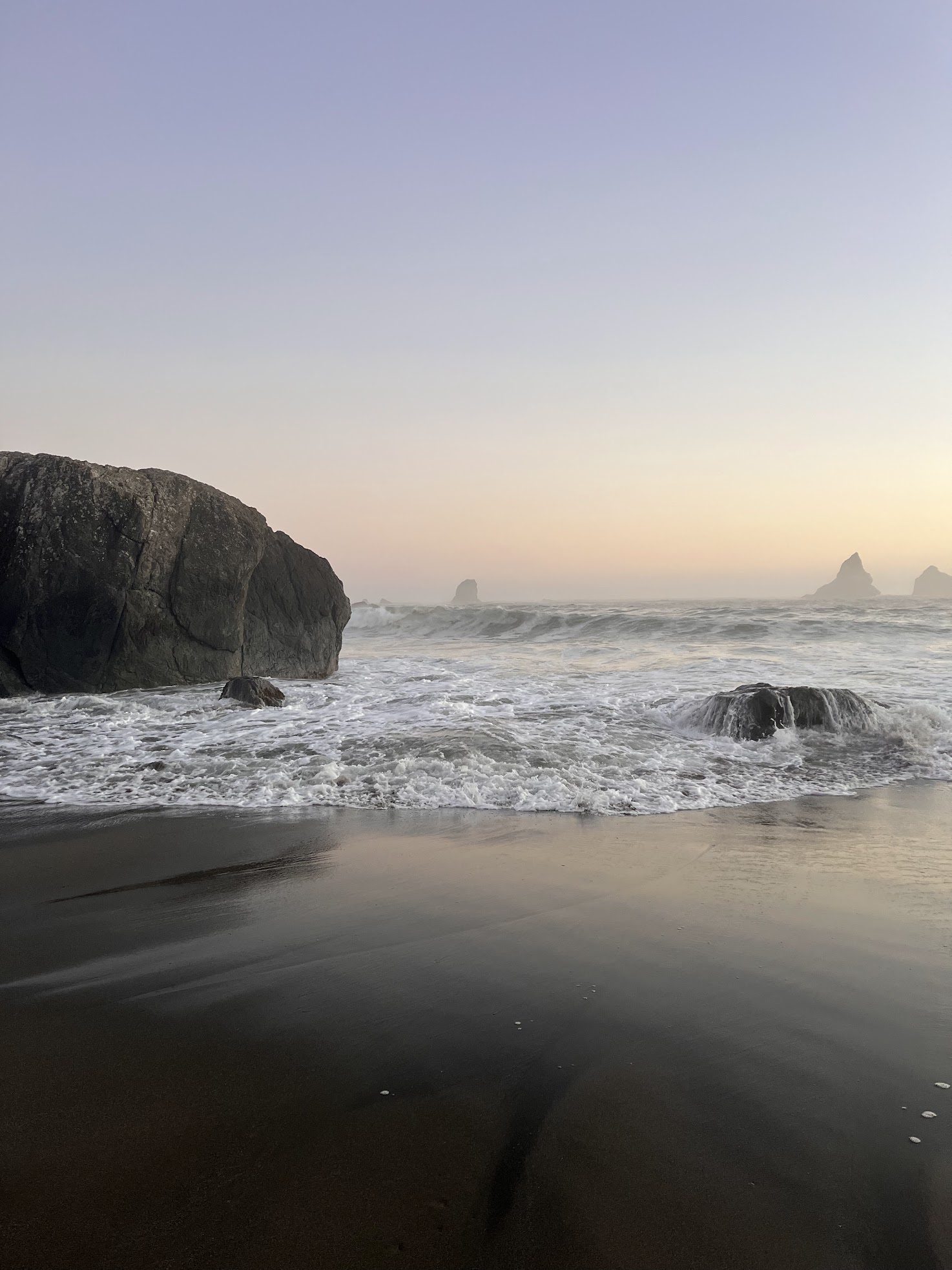 Waves breaking around a sea stack at Lone Ranch Beach at dusk.