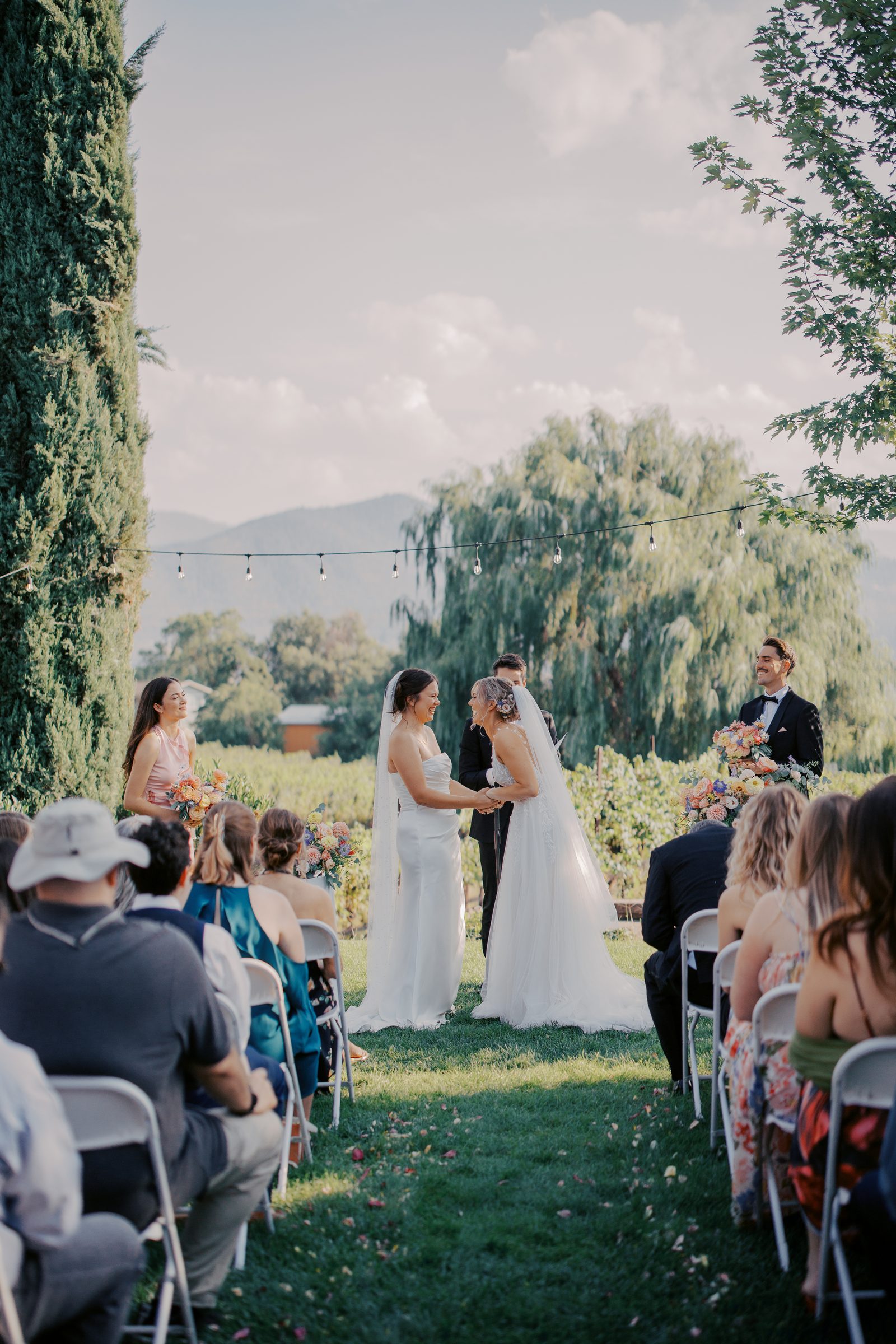 Outdoor vineyard wedding ceremony under string lights.