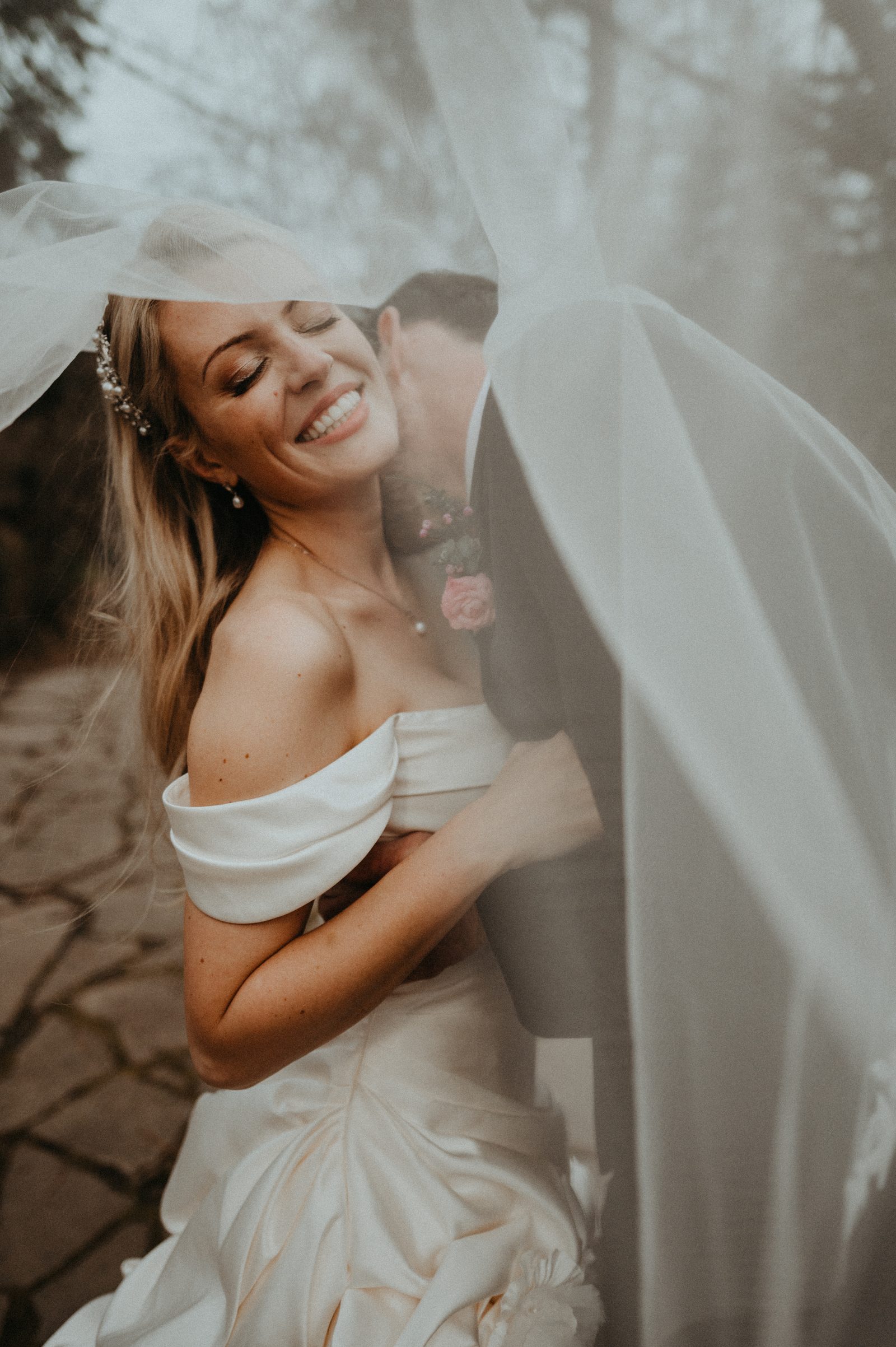 Bride laughing beneath her veil.