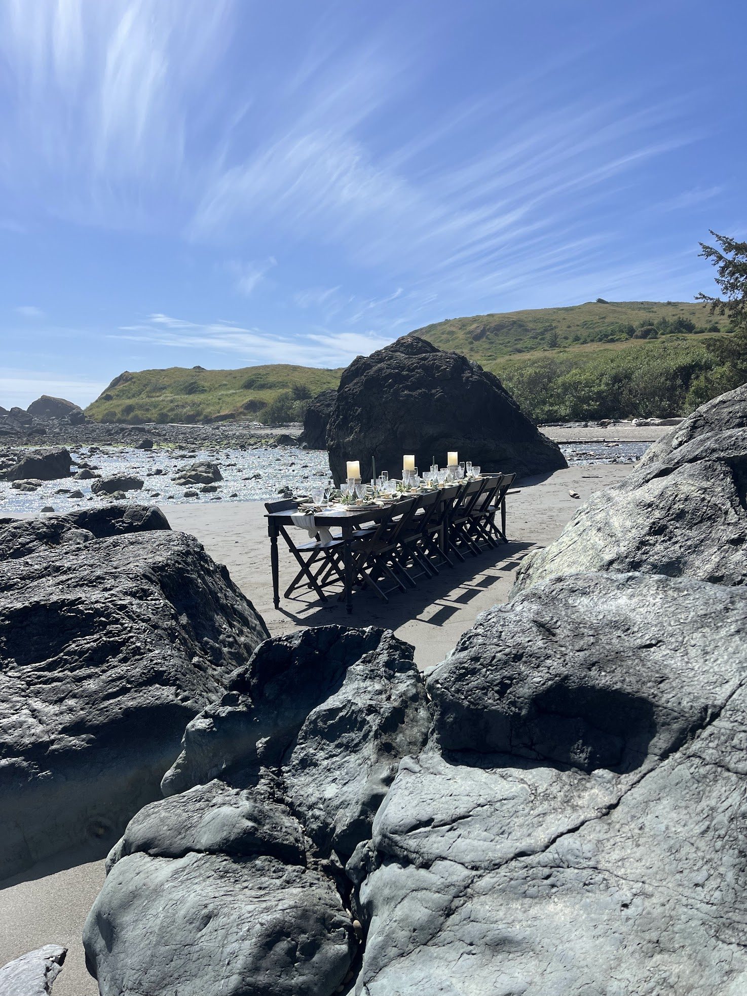 Long candlelit dinner table set between the rocks at Lone Ranch Beach.