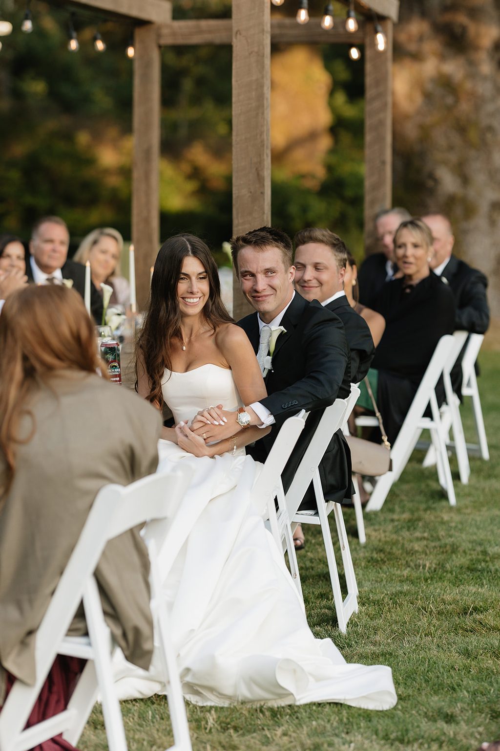 Couple seated among smiling guests at a Crook Point ceremony.